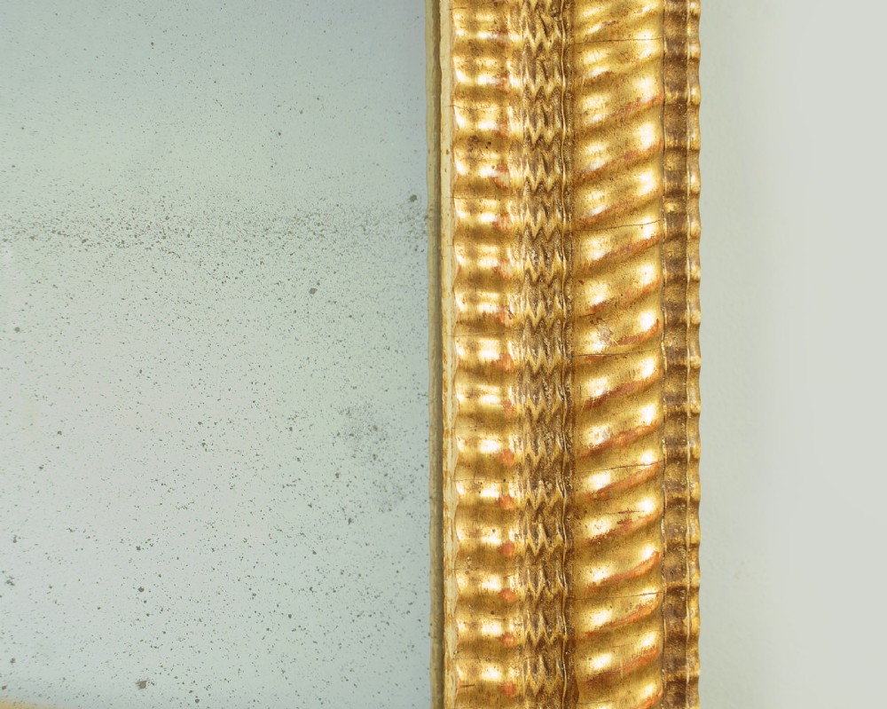 A small rectangular 19th-century French giltwood mirror with textured frame moulding and carved corner rosettes. View V