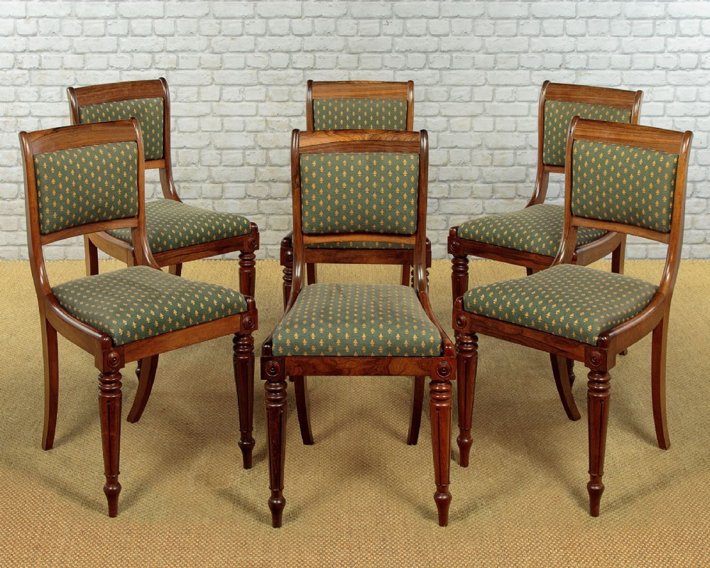 Set of six late Regency rosewood dining chairs featuring reeded front legs, sabre rear legs, and green patterned fabric upholstered seats and back panels.