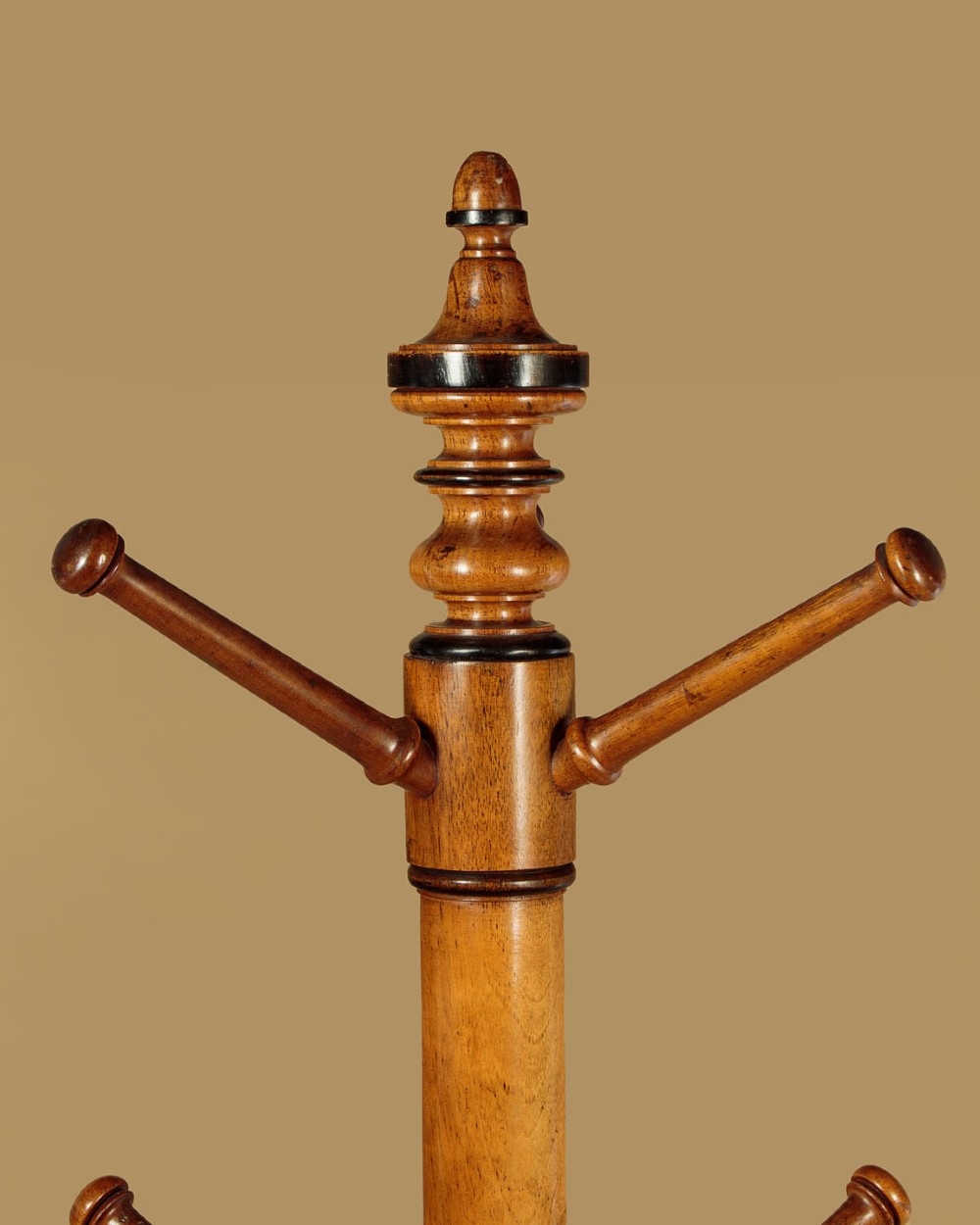 A tall Victorian turned walnut hall tree featuring multi-tiered pegs on a central column supported by a carved four-legged base. View III