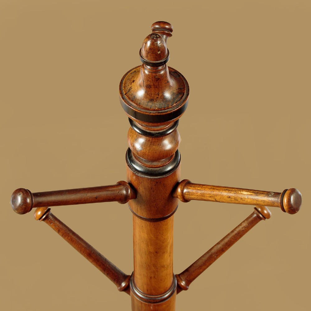 A tall Victorian turned walnut hall tree featuring multi-tiered pegs on a central column supported by a carved four-legged base. View IV