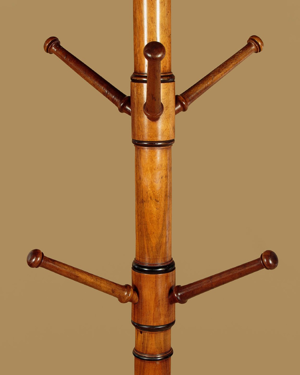 A tall Victorian turned walnut hall tree featuring multi-tiered pegs on a central column supported by a carved four-legged base. View V