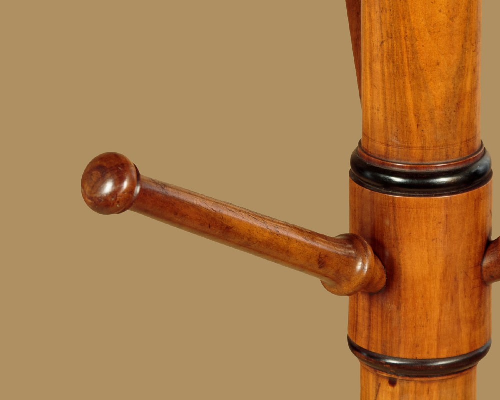 A tall Victorian turned walnut hall tree featuring multi-tiered pegs on a central column supported by a carved four-legged base. View VII