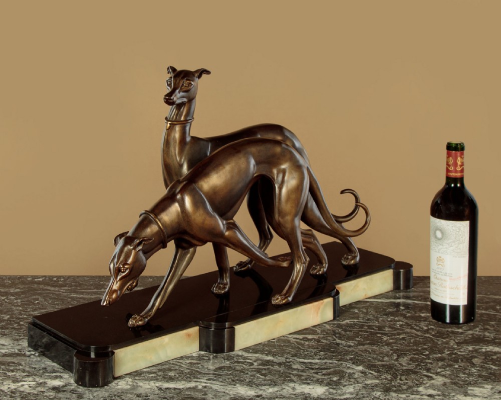 An Art Deco dark bronze sculpture featuring two sleek greyhounds poised on a stepped black marble and cream onyx base. View II