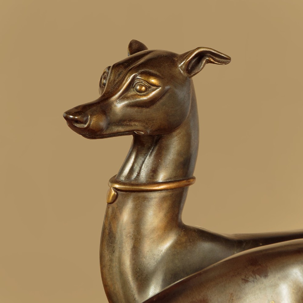 An Art Deco dark bronze sculpture featuring two sleek greyhounds poised on a stepped black marble and cream onyx base. View V