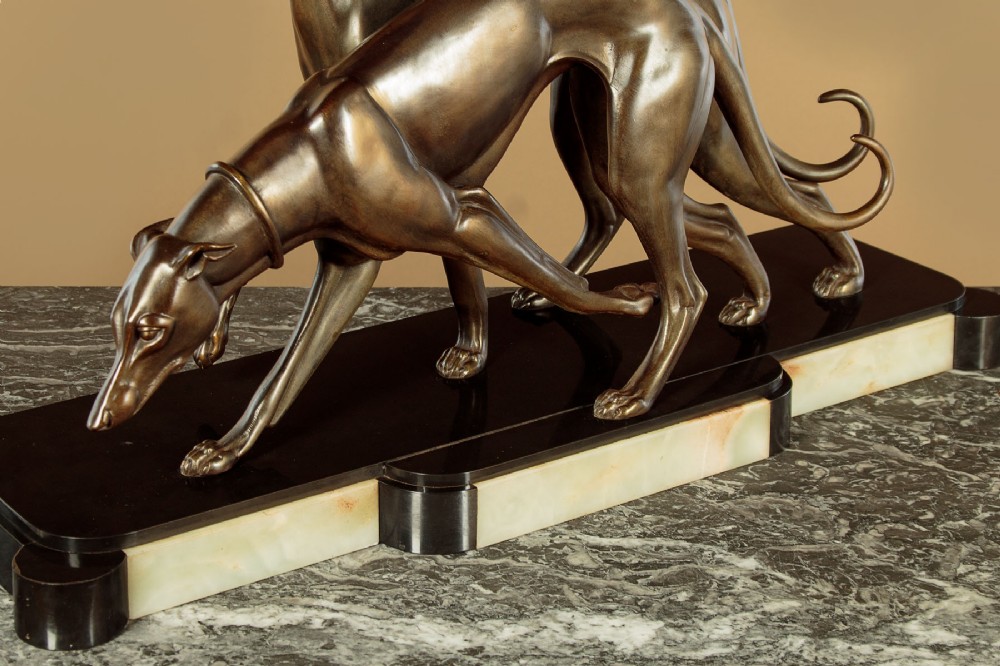 An Art Deco dark bronze sculpture featuring two sleek greyhounds poised on a stepped black marble and cream onyx base. View IX