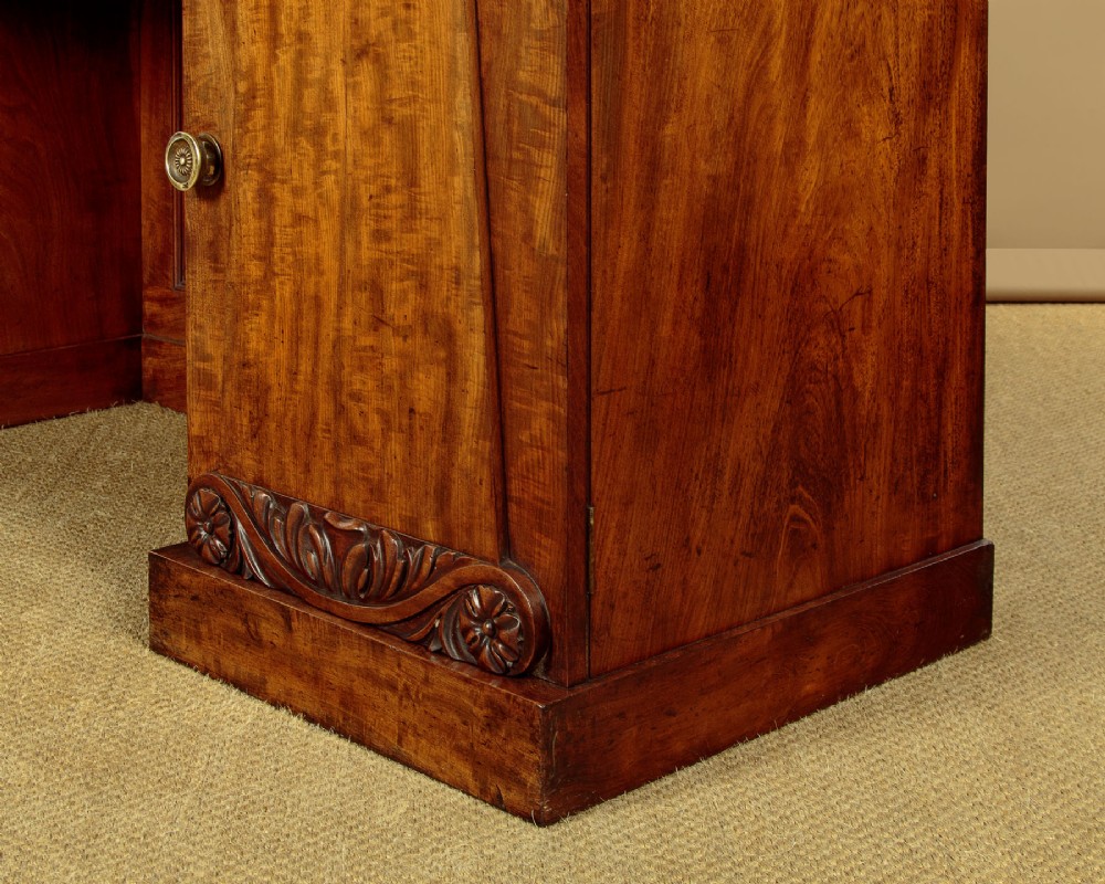 An early Victorian flame mahogany pedestal sideboard featuring carved scrollwork across the central apron and pedestal cupboards set on plinth bases. View XIII