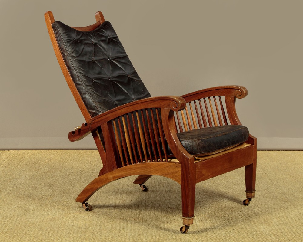 An Arts and Crafts adjustable reclining armchair in polished hardwood with slatted side panels and dark brown tufted leather cushions. View II