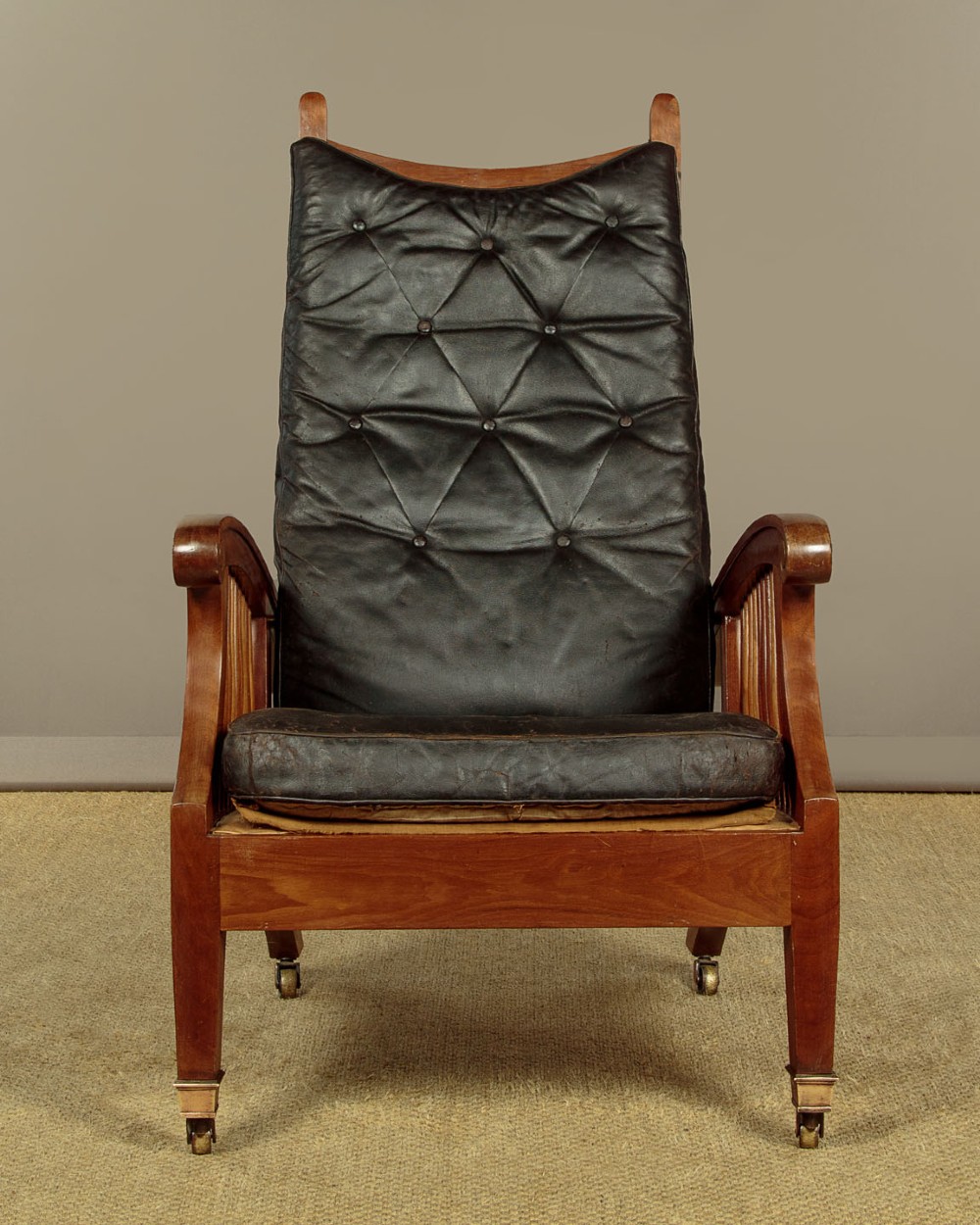 An Arts and Crafts adjustable reclining armchair in polished hardwood with slatted side panels and dark brown tufted leather cushions. View III
