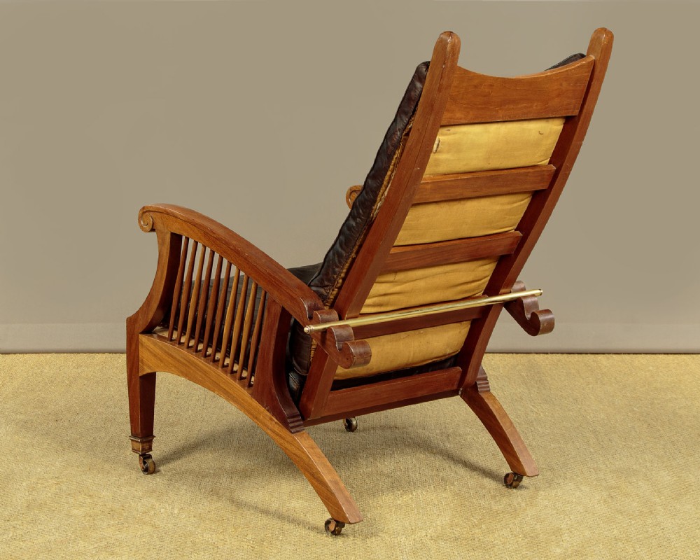 An Arts and Crafts adjustable reclining armchair in polished hardwood with slatted side panels and dark brown tufted leather cushions. View V