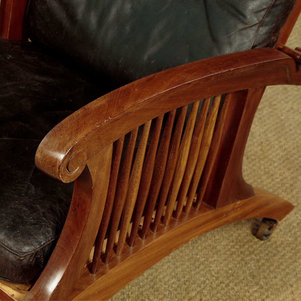 An Arts and Crafts adjustable reclining armchair in polished hardwood with slatted side panels and dark brown tufted leather cushions. View IX
