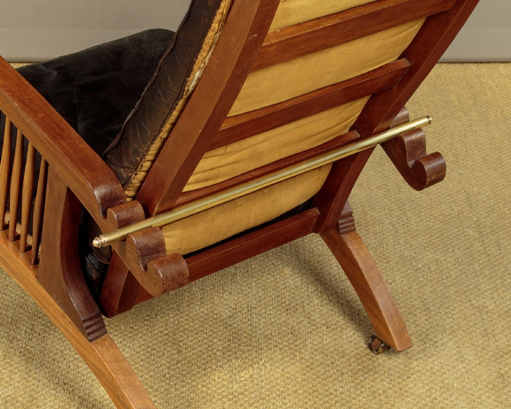 An Arts and Crafts adjustable reclining armchair in polished hardwood with slatted side panels and dark brown tufted leather cushions. View XIV