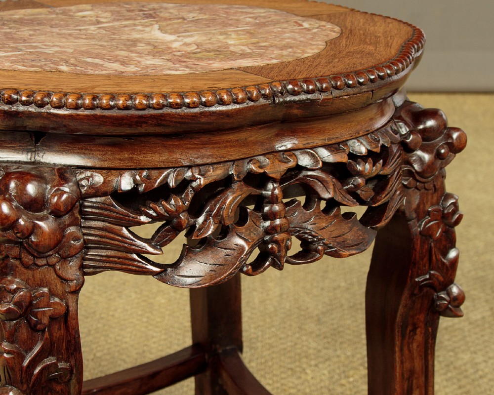 A low circular dark hardwood side table featuring an inset pink marble top, beaded rim, carved floral openwork apron, and claw feet. View VI