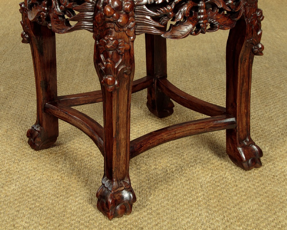 A low circular dark hardwood side table featuring an inset pink marble top, beaded rim, carved floral openwork apron, and claw feet. View VIII