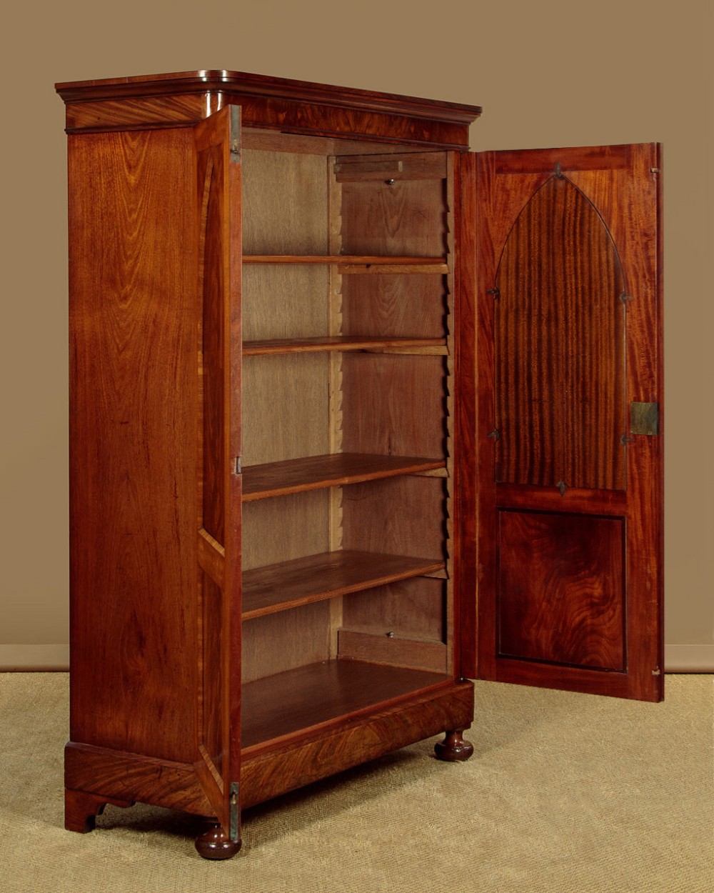 A mid-19th century compact Victorian mahogany wardrobe with flame mahogany arched door panels and round bun feet. View IV