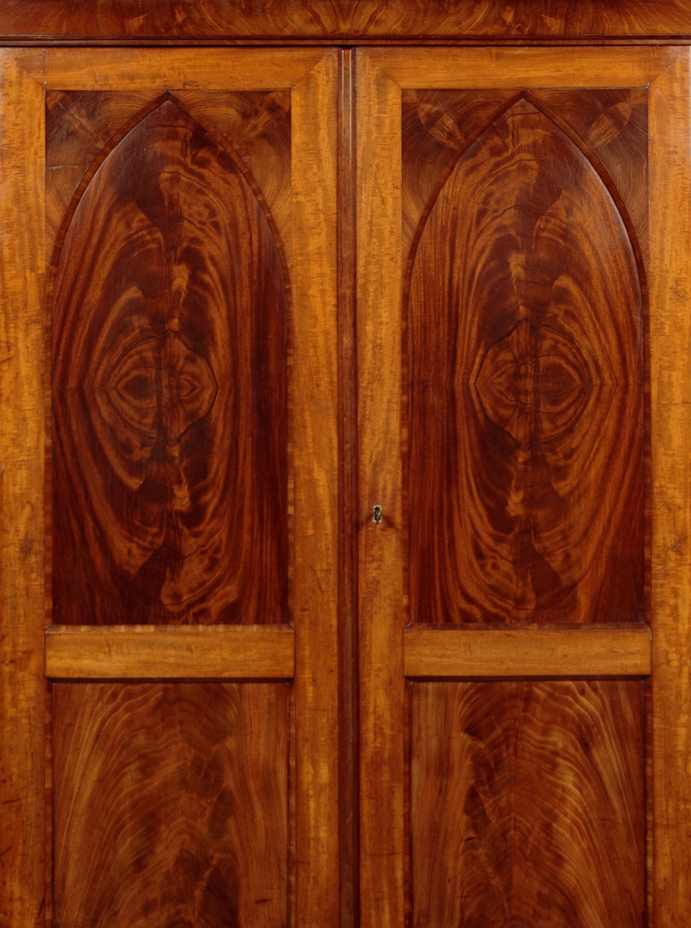 A mid-19th century compact Victorian mahogany wardrobe with flame mahogany arched door panels and round bun feet. View VI