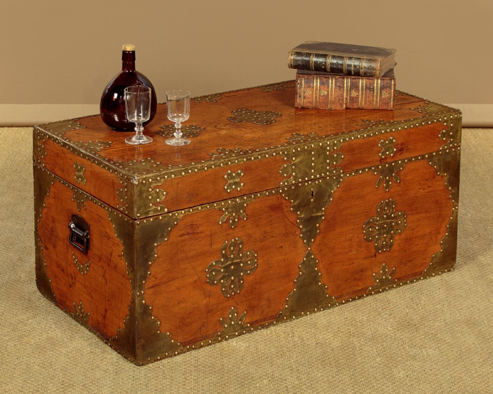 A rectangular warm brown wooden chest decorated with pierced brass corner brackets, floral mounts, and studded detailing across the top and front. View II