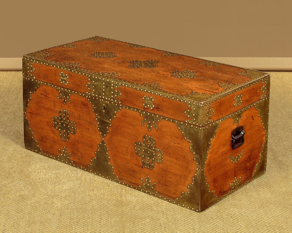 A rectangular warm brown wooden chest decorated with pierced brass corner brackets, floral mounts, and studded detailing across the top and front. View IV