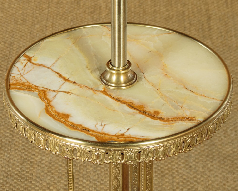 An Edwardian brass standard lamp featuring an integrated circular onyx wine table with a pierced gallery trim atop a scrolling tripod base. View IV