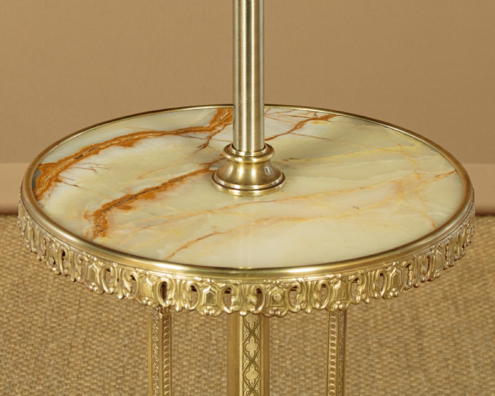 An Edwardian brass standard lamp featuring an integrated circular onyx wine table with a pierced gallery trim atop a scrolling tripod base. View V