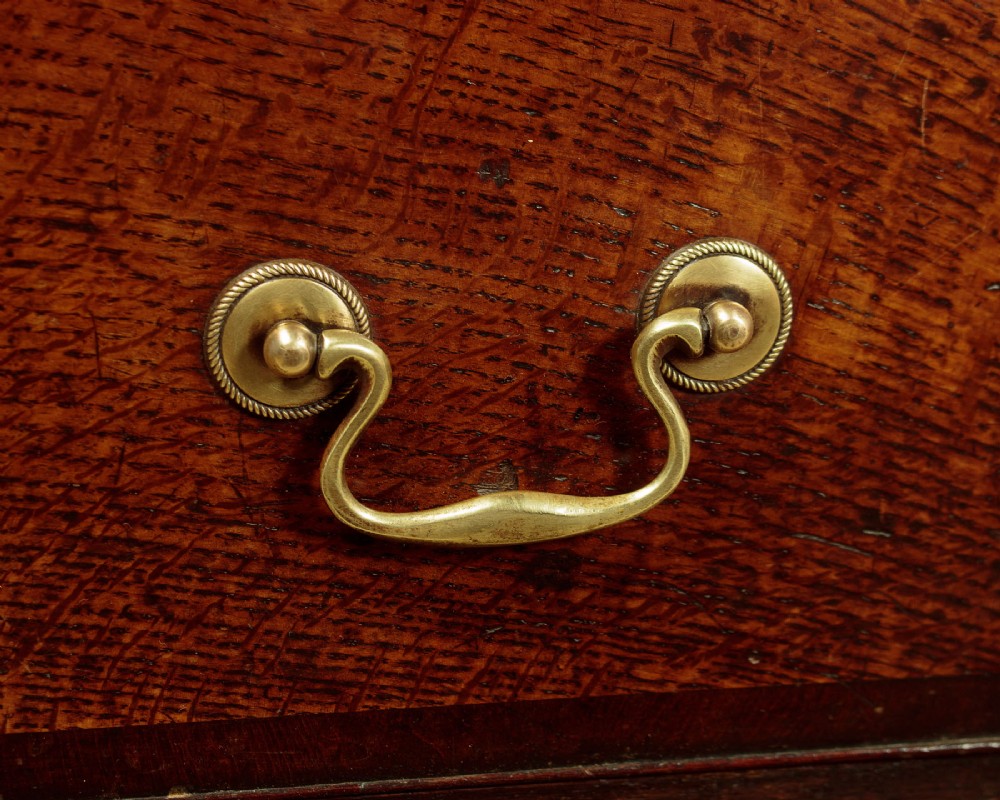 A long Georgian oak dresser base featuring multiple drawers with brass handles flanking a central double door cupboard, set on bracket feet. View X