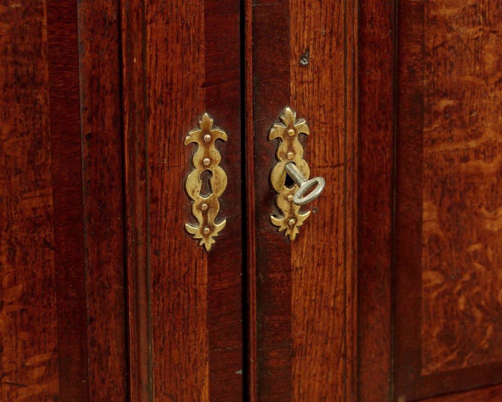 A long Georgian oak dresser base featuring multiple drawers with brass handles flanking a central double door cupboard, set on bracket feet. View XIII