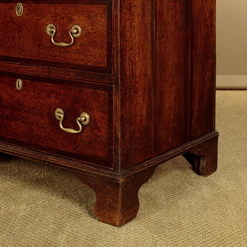 A long Georgian oak dresser base featuring multiple drawers with brass handles flanking a central double door cupboard, set on bracket feet. View XIV