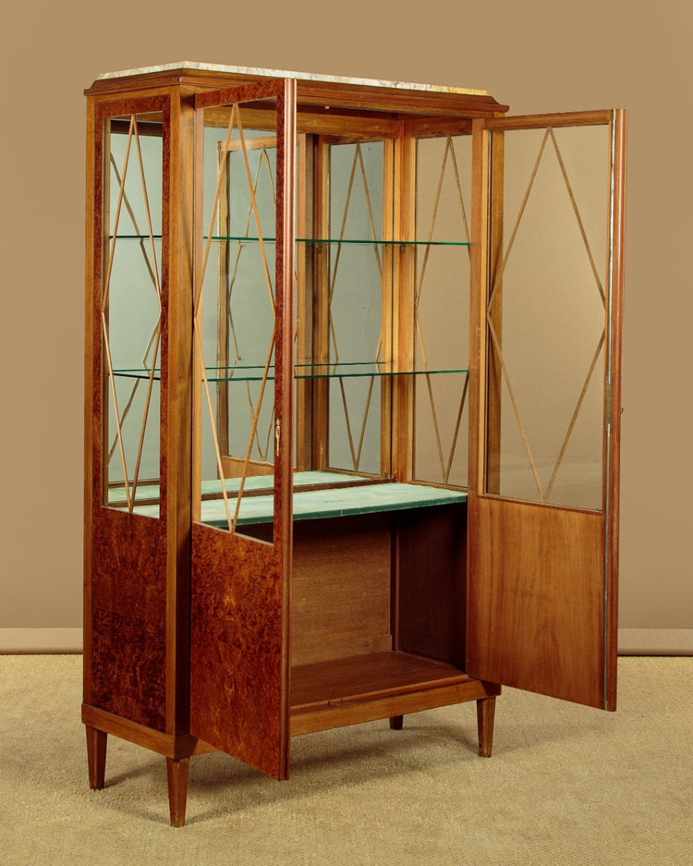 An Art Deco amboyna wood display cabinet featuring diamond-patterned glazing, glass shelves, a marble top, and tapered square legs. View III