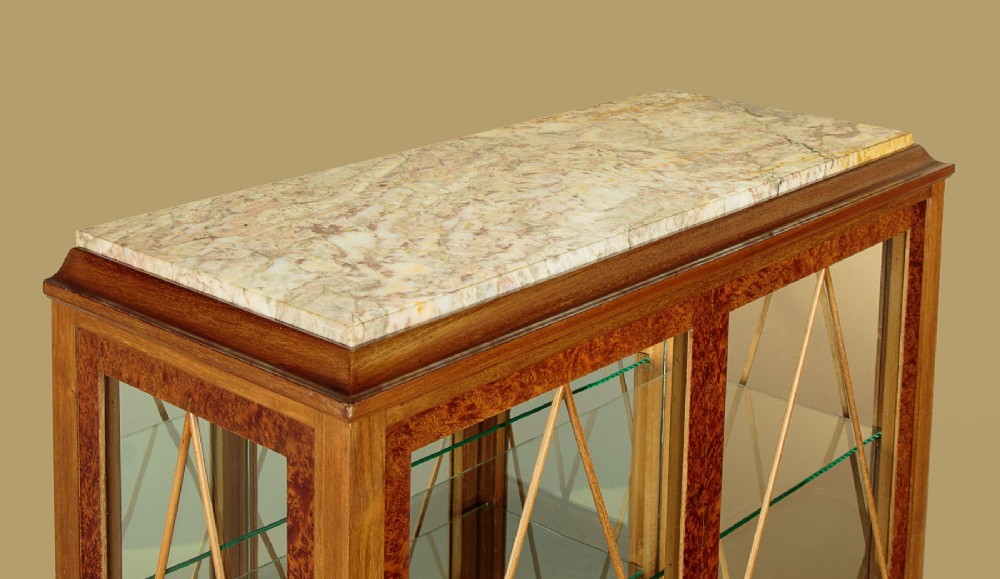 An Art Deco amboyna wood display cabinet featuring diamond-patterned glazing, glass shelves, a marble top, and tapered square legs. View IV