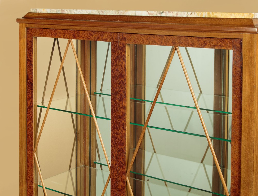 An Art Deco amboyna wood display cabinet featuring diamond-patterned glazing, glass shelves, a marble top, and tapered square legs. View V