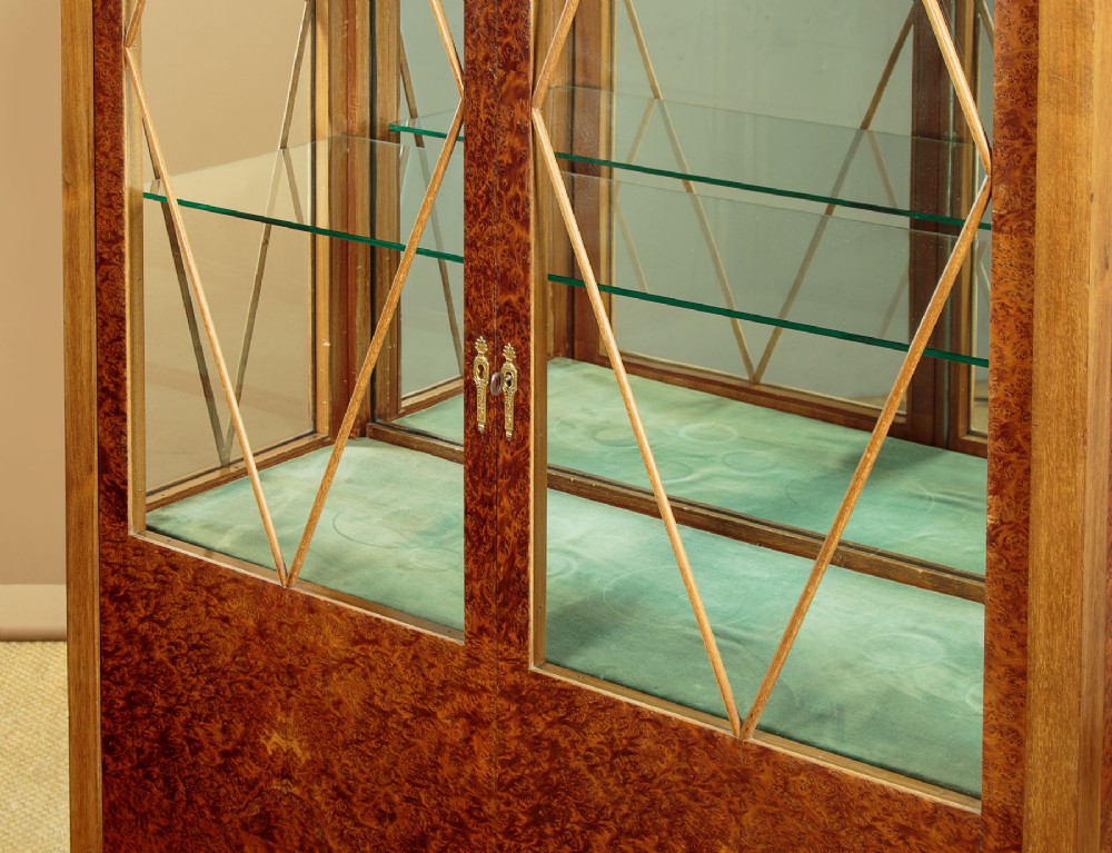 An Art Deco amboyna wood display cabinet featuring diamond-patterned glazing, glass shelves, a marble top, and tapered square legs. View VI