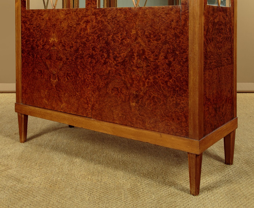 An Art Deco amboyna wood display cabinet featuring diamond-patterned glazing, glass shelves, a marble top, and tapered square legs. View VIII
