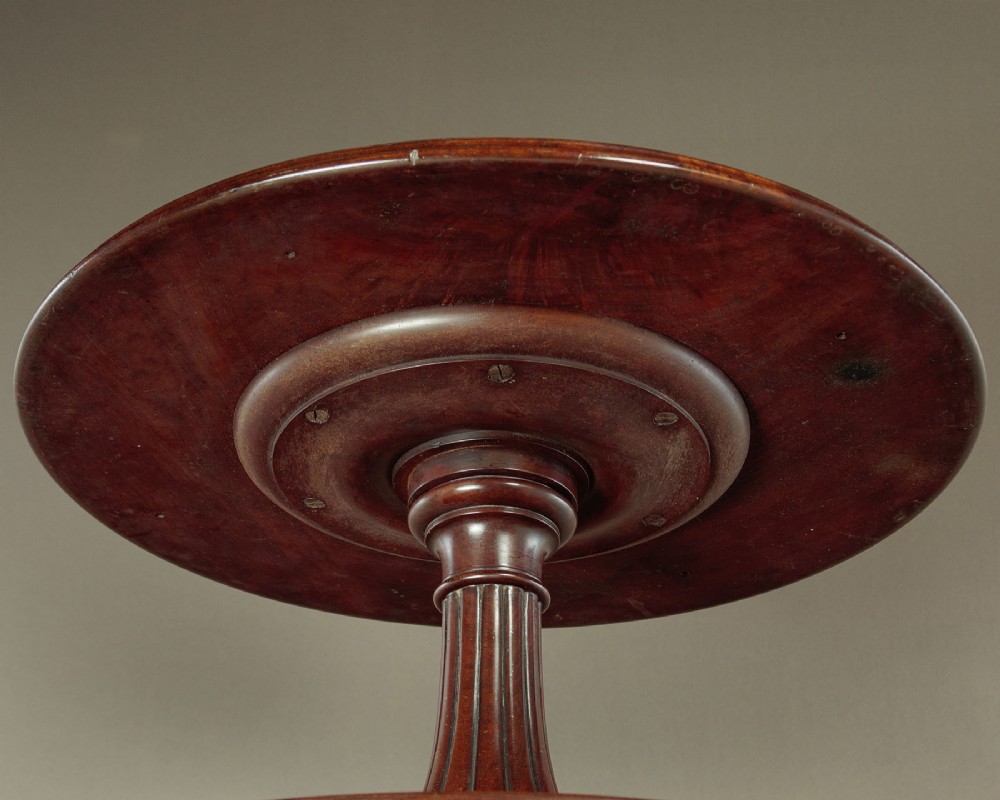 A mahogany three-tier dumb waiter featuring graduated circular trays supported by fluted central columns on a tripod base with brass castors. View III