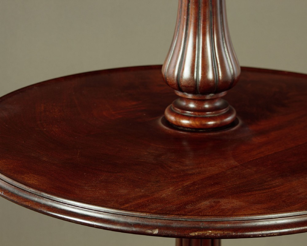 A mahogany three-tier dumb waiter featuring graduated circular trays supported by fluted central columns on a tripod base with brass castors. View VII