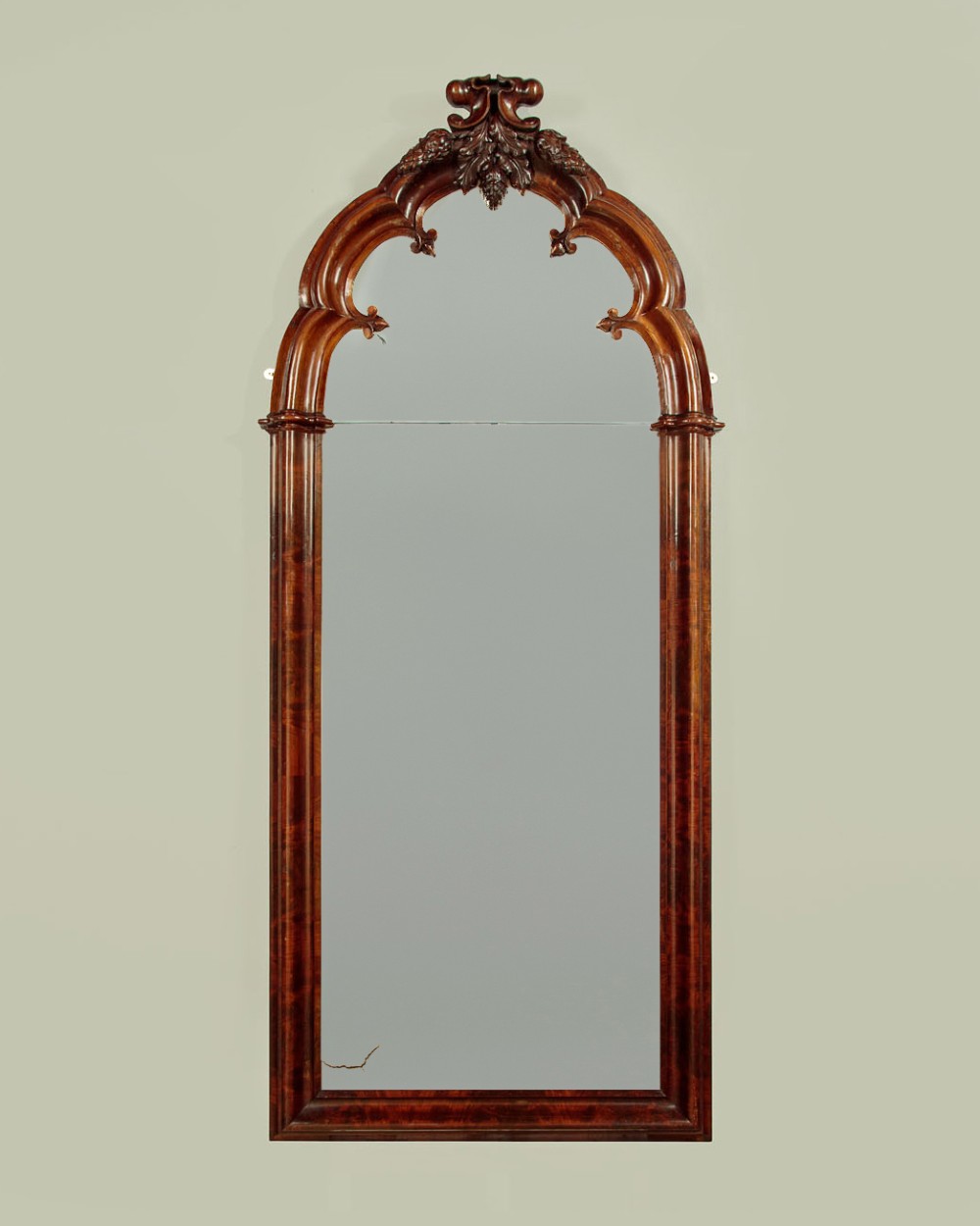 A tall and narrow 19th-century dark mahogany pier mirror featuring a carved Gothic arch cresting and moulded side pillars.