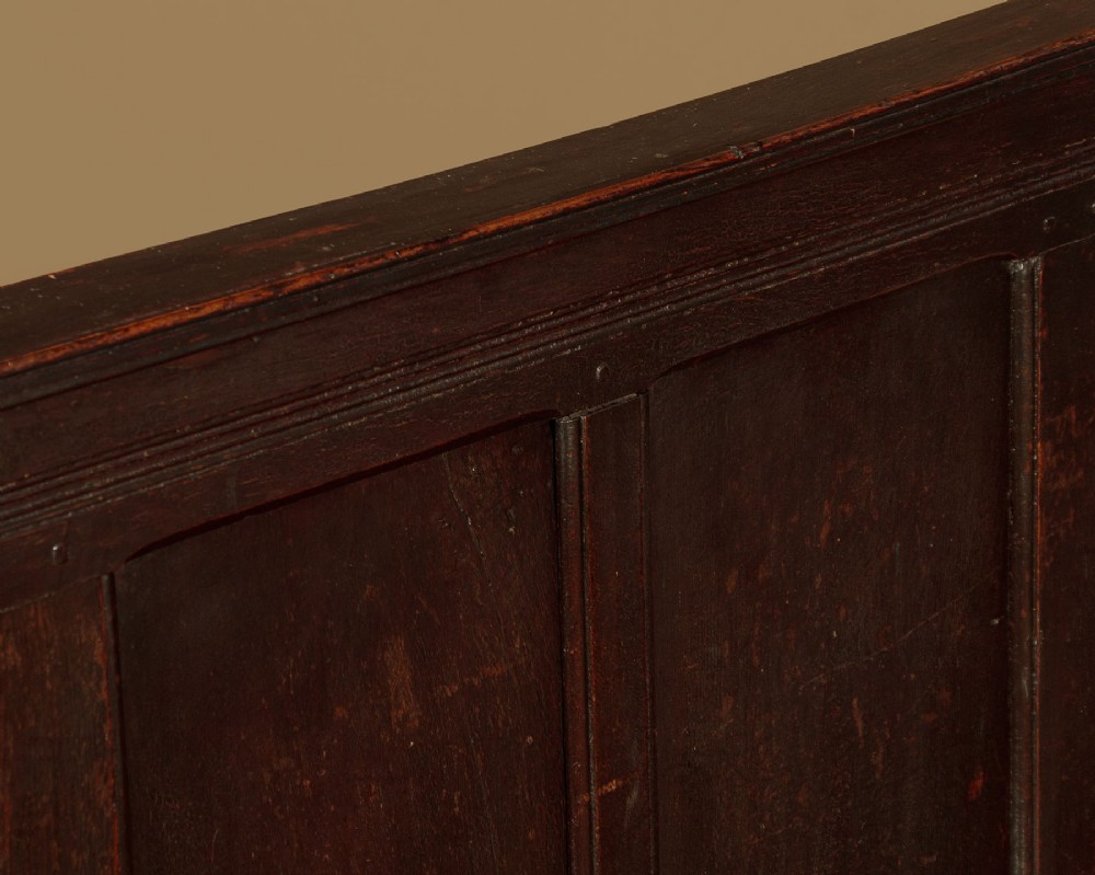 An 18th-century dark oak settle featuring a tall four-panel backrest, flat armrests, and a solid timber seat on straight legs. View IV