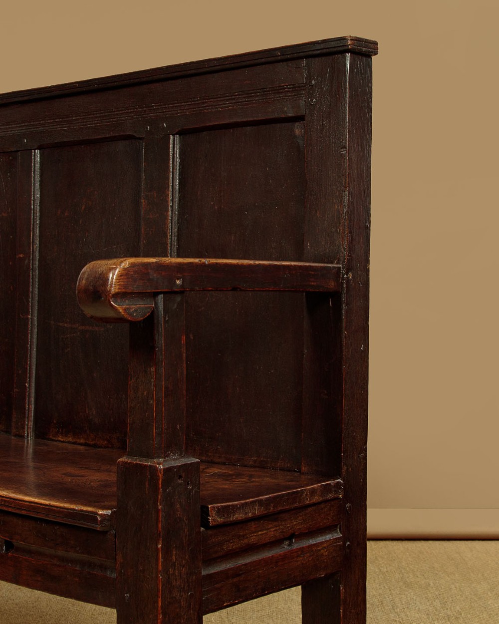 An 18th-century dark oak settle featuring a tall four-panel backrest, flat armrests, and a solid timber seat on straight legs. View IX