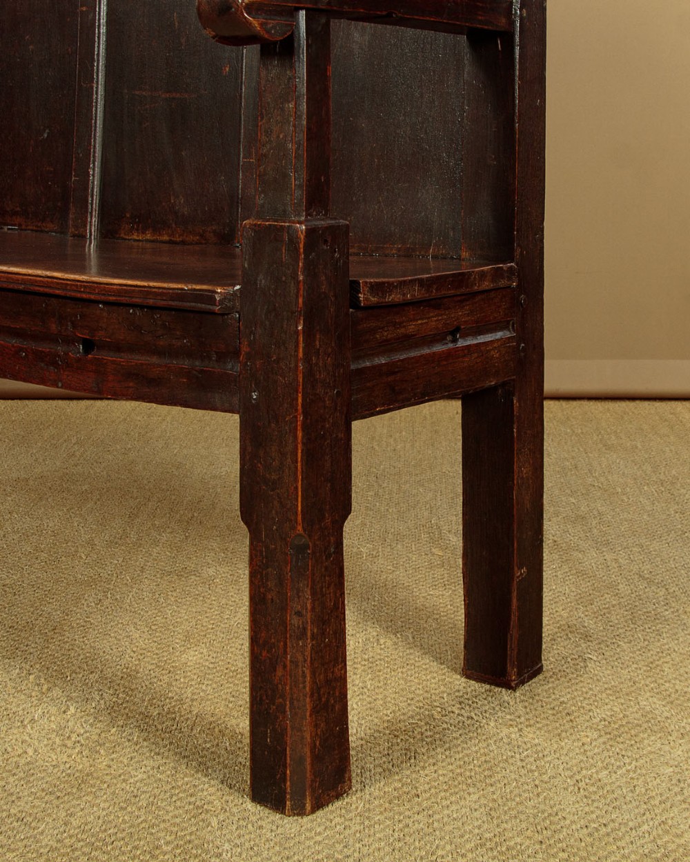 An 18th-century dark oak settle featuring a tall four-panel backrest, flat armrests, and a solid timber seat on straight legs. View XI