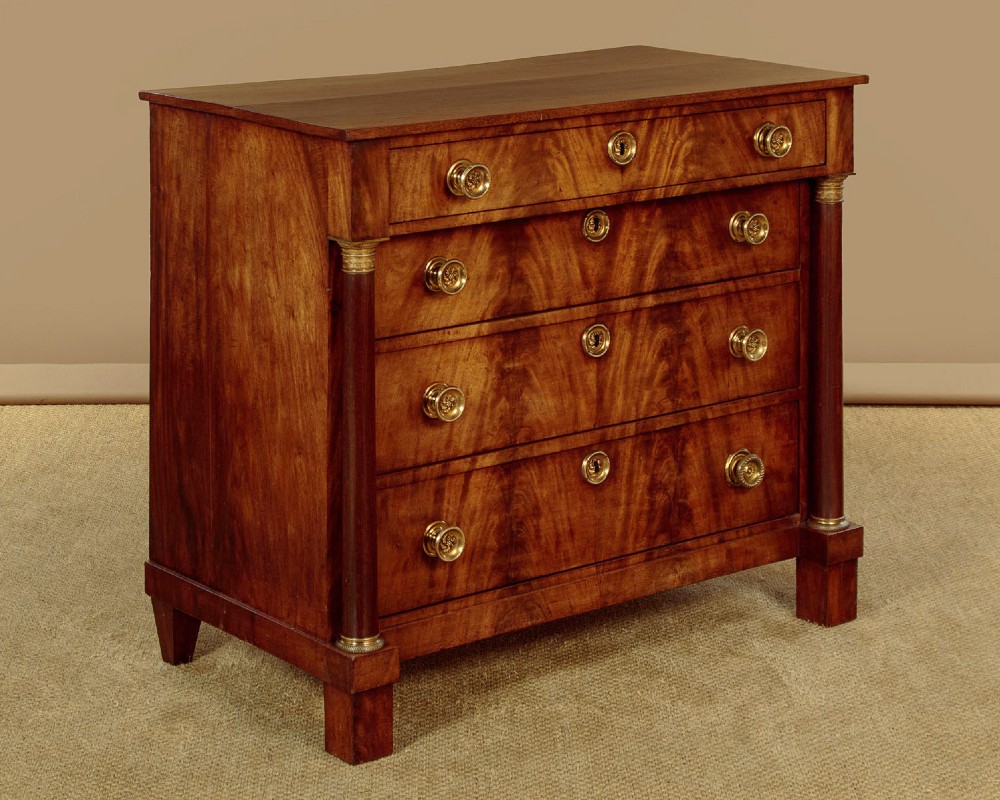 A small 19th-century Empire style mahogany chest featuring four drawers with flame veneer finishes, brass knob handles, keyhole escutcheons, and flank columns. View II