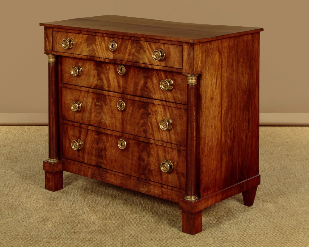 A small 19th-century Empire style mahogany chest featuring four drawers with flame veneer finishes, brass knob handles, keyhole escutcheons, and flank columns. View III