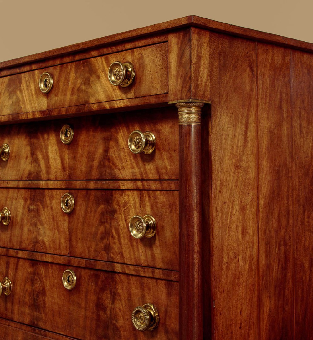 A small 19th-century Empire style mahogany chest featuring four drawers with flame veneer finishes, brass knob handles, keyhole escutcheons, and flank columns. View IX