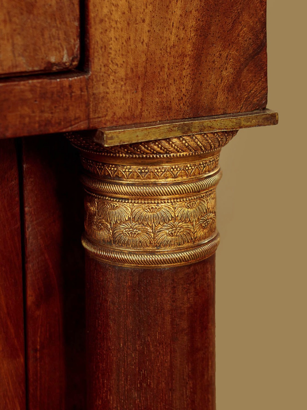 A small 19th-century Empire style mahogany chest featuring four drawers with flame veneer finishes, brass knob handles, keyhole escutcheons, and flank columns. View X