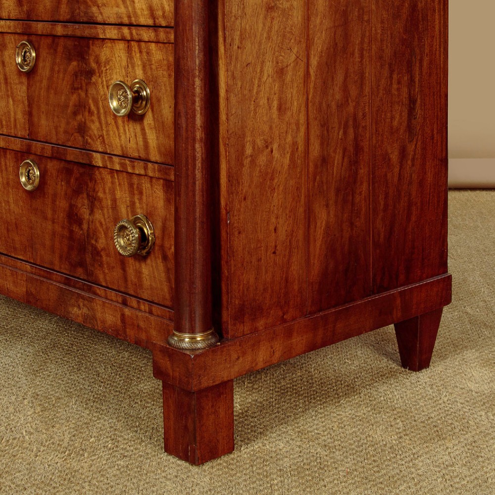A small 19th-century Empire style mahogany chest featuring four drawers with flame veneer finishes, brass knob handles, keyhole escutcheons, and flank columns. View XIII