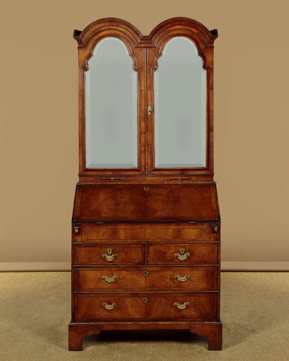 A Queen Anne style burr walnut bureau cabinet featuring a double-domed top with twin mirrored doors above a slant-front writing slope and lower drawers.