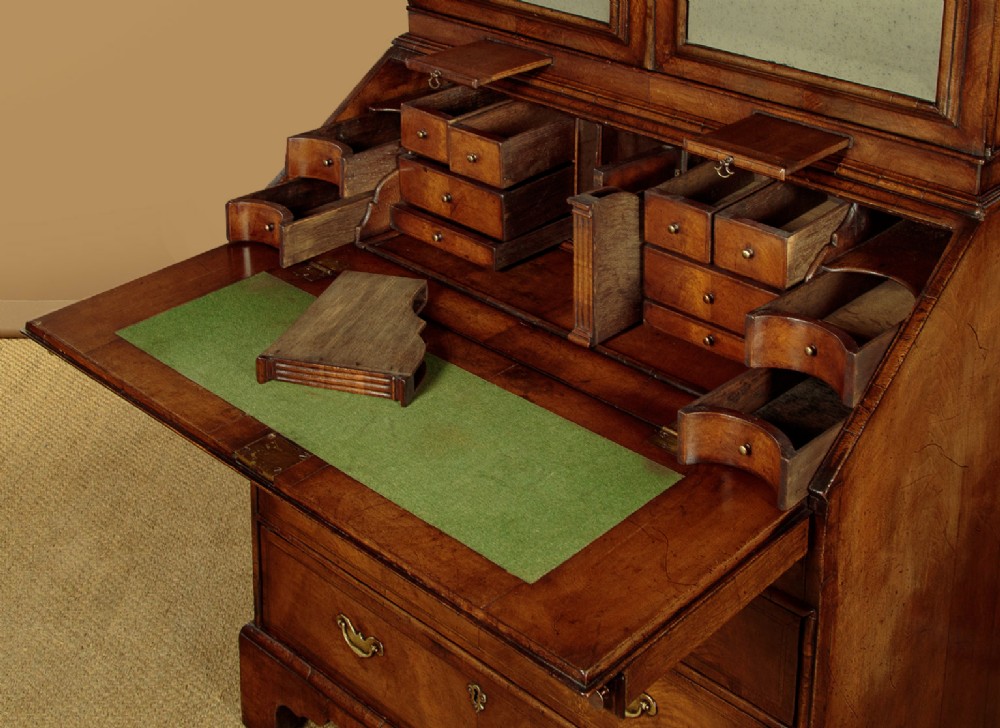 A Queen Anne style burr walnut bureau cabinet featuring a double-domed top with twin mirrored doors above a slant-front writing slope and lower drawers. View X