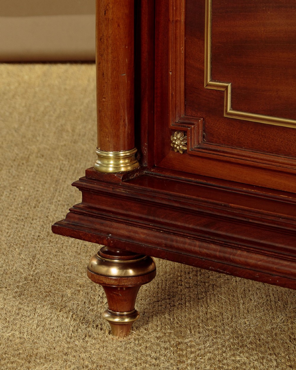 A tall, narrow mahogany bookcase featuring a single glazed door, internal wooden shelves, brass fluted column accents, and a brass gallery top. View XI
