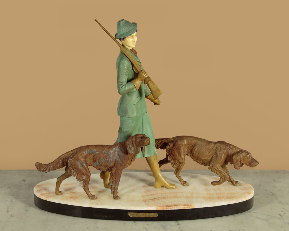 Art Deco figure group depicting a huntress in a green suit with two hunting dogs mounted on an oval marble base. View III