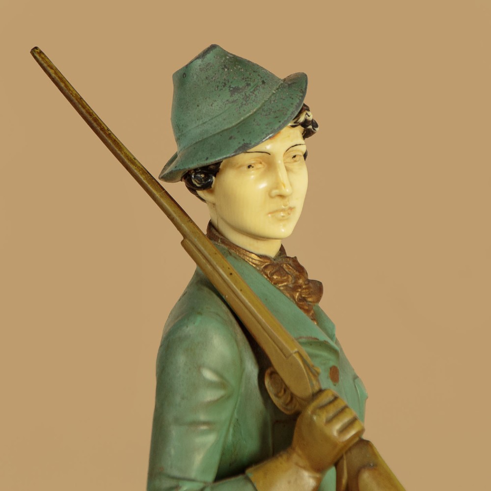 Art Deco figure group depicting a huntress in a green suit with two hunting dogs mounted on an oval marble base. View VII
