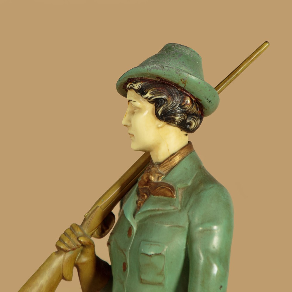 Art Deco figure group depicting a huntress in a green suit with two hunting dogs mounted on an oval marble base. View VIII
