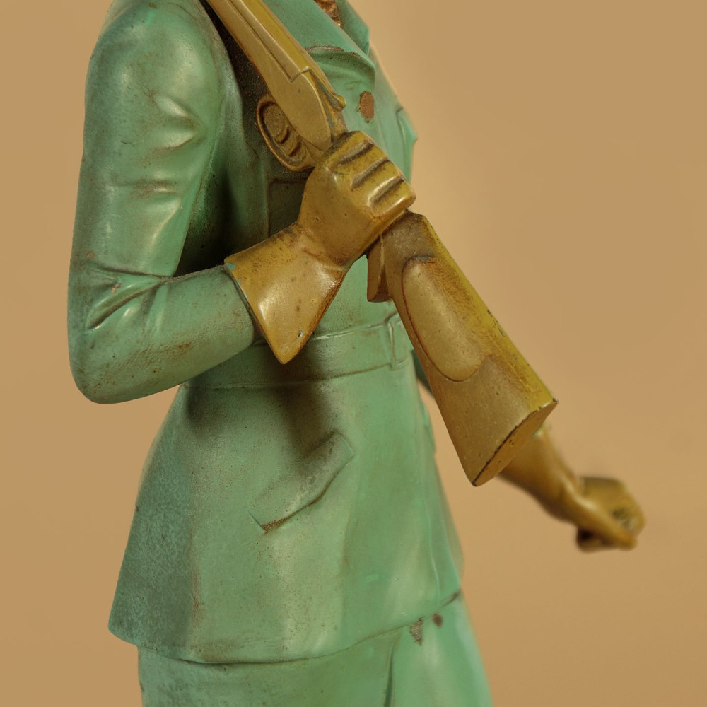 Art Deco figure group depicting a huntress in a green suit with two hunting dogs mounted on an oval marble base. View IX