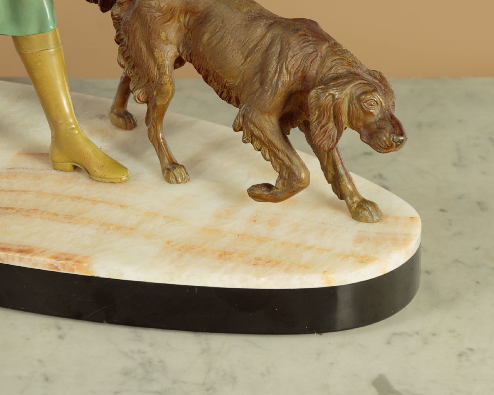Art Deco figure group depicting a huntress in a green suit with two hunting dogs mounted on an oval marble base. View XIII